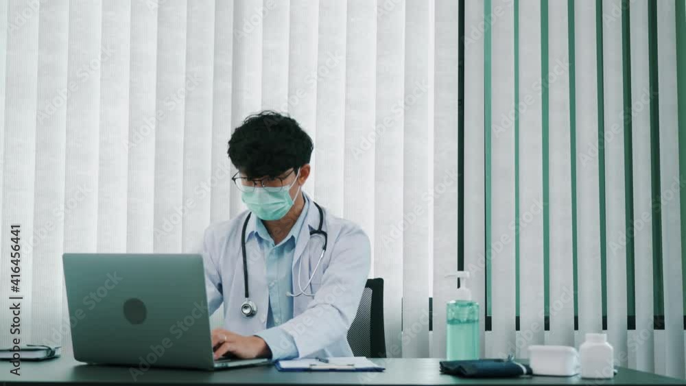 Asian doctor is working on a laptop computer and writes the patient's history in the office. Asian doctor is working on a laptop computer and writes the patient's history in the office.