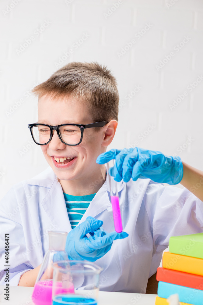 A schoolboy studies multi-colored substances in test tubes, conducts experiments - a portrait on a white background. Concept for the study of coronavirus in the laboratory A schoolboy studies multi-colored substances in test tubes, conducts experiments - a portrait on a white background. Concept for the study of coronavirus in the laboratory