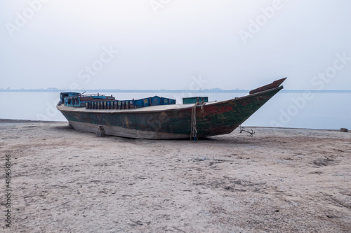 Wooden fishing boat on the beach with foggy sky.