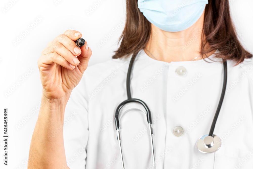 Doctor with mask writing with a black marker pen on a white background Doctor with mask writing with a black marker pen on a white background