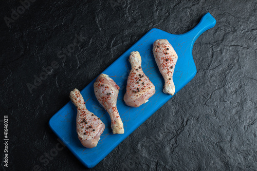 Top view raw chicken drumstick on blue wooden board
