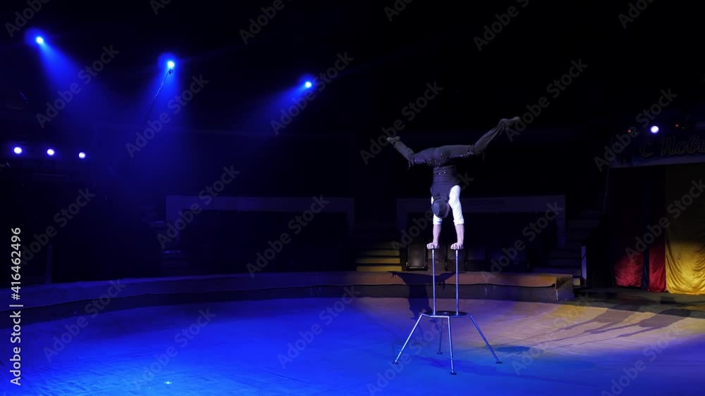 A man of athletic build performs complex gymnastic exercises in a circus A man of athletic build performs complex gymnastic exercises in a circus