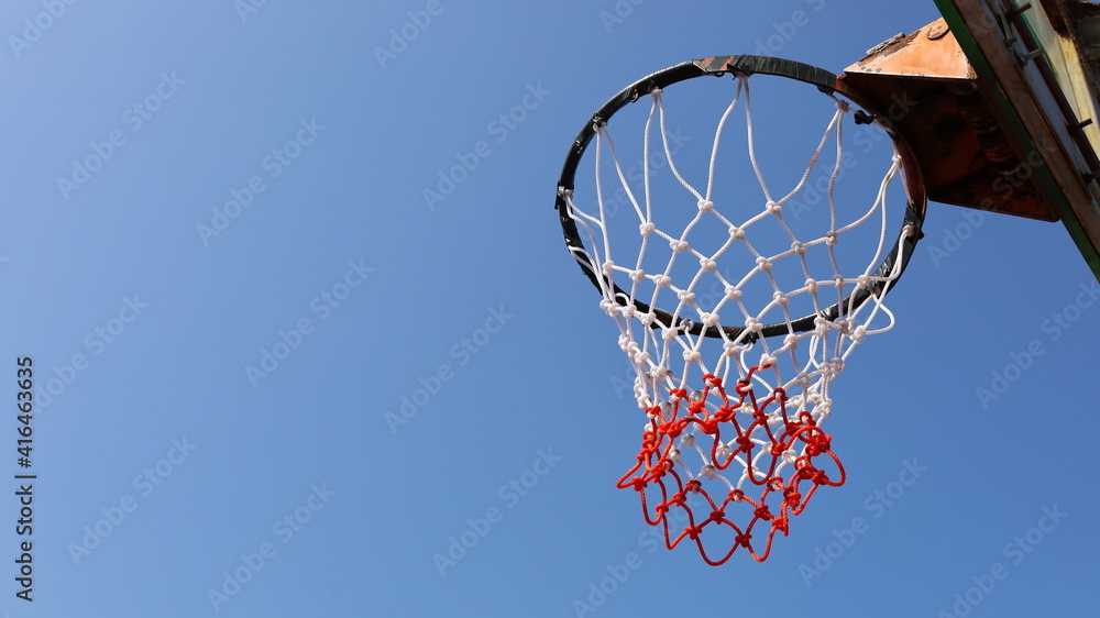Complete basketball net. New white and red mesh in bottom view On a clear blue sky background with copy space. Selective focus