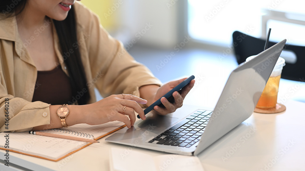 Young woman sitting in cafe using mobile phone and working with computer laptop. Young woman sitting in cafe using mobile phone and working with computer laptop.