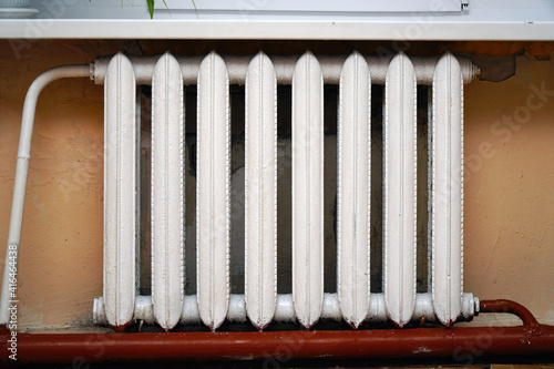 Old cast-iron radiator on the background of gray wall.