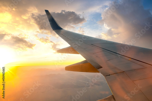 View from airplane on the aircraft white wing flying over desert landscape in sunny morning. Air travel and transportation concept.