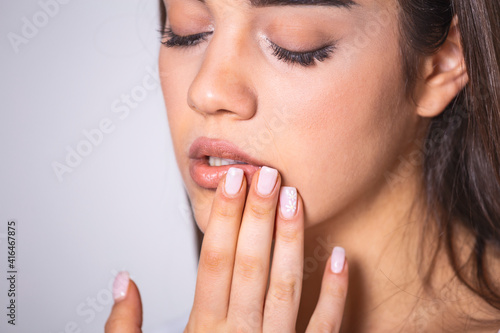 Young woman touches her Mouth - Concept showing avoid touch face to protect and prevent form covid-19  sars cov 2 or coronavirus outbreak or spreading.