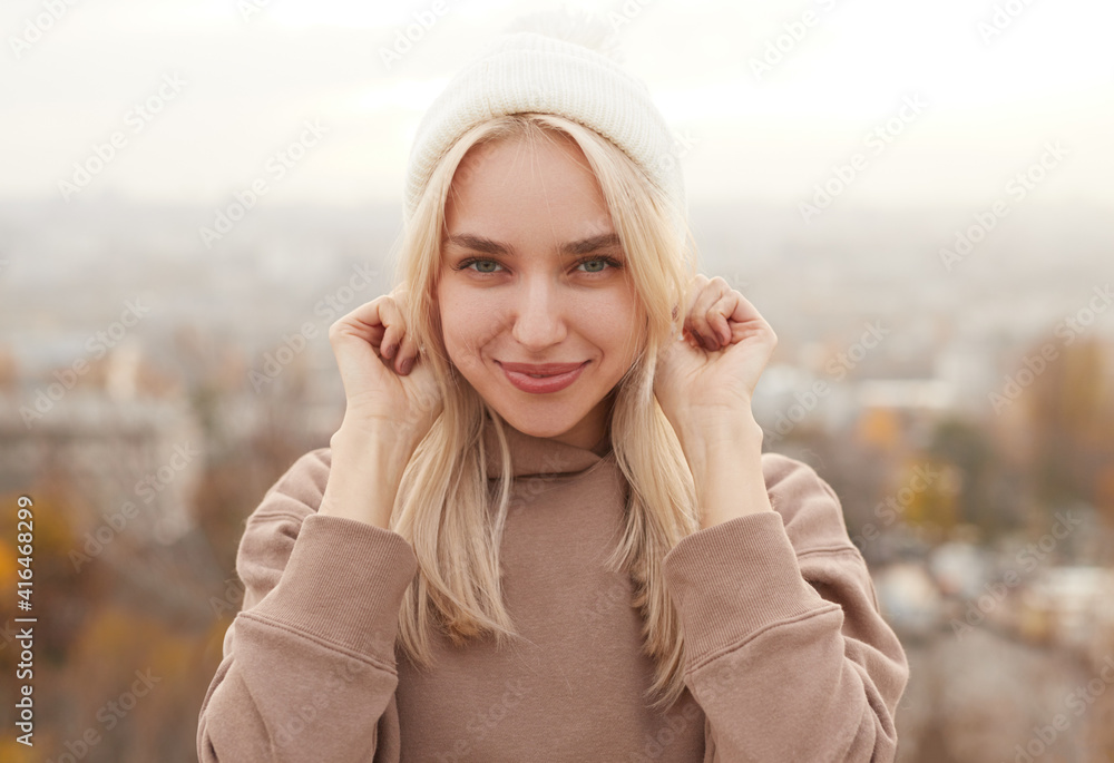 Smiling young woman in knitted hat looking at camera