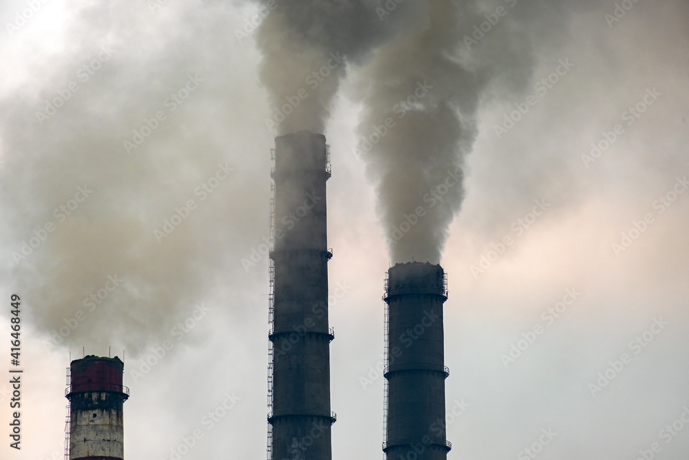 Coal power plant high pipes with black smoke moving up polluting atmosphere.