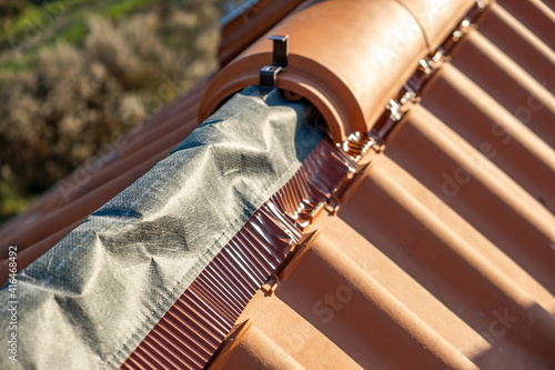 Foto Closeup of yellow ceramic roofing ridge tiles on top of residential building roof under construction