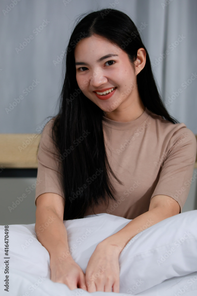 Image of Portrait smiling asian beautiful woman wearing a brown dress hold pillow.Holding white pillows on the bed in the bedroom at home. Concept Smile woman cozy. Image of Portrait smiling asian beautiful woman wearing a brown dress hold pillow.Holding white pillows on the bed in the bedroom at home. Concept Smile woman cozy.