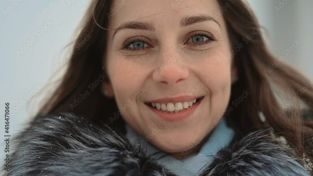 Close-up portrait of woman looking at camera posing in winter clothes and smiling Close-up portrait of woman looking at camera posing in winter clothes and smiling