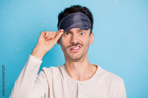 Close-up portrait of funky irritated mature guy putting eye sleep mask on isolated over bright blue color background photo