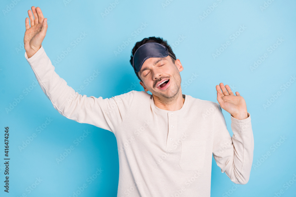Fototapeta premium Portrait of nice healthy sleepy guy wearing sleep mask stretching yawning awakening isolated over bright blue color background