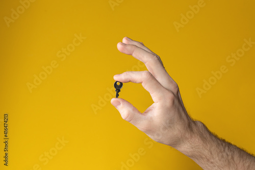 Male hand holding key on yellow background. concept of solution, success, opportunity.