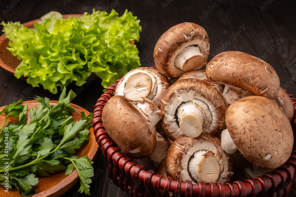mushrooms in a basket with lettuce and herbs on a dark wooden background mushrooms in a basket with lettuce and herbs on a dark wooden background