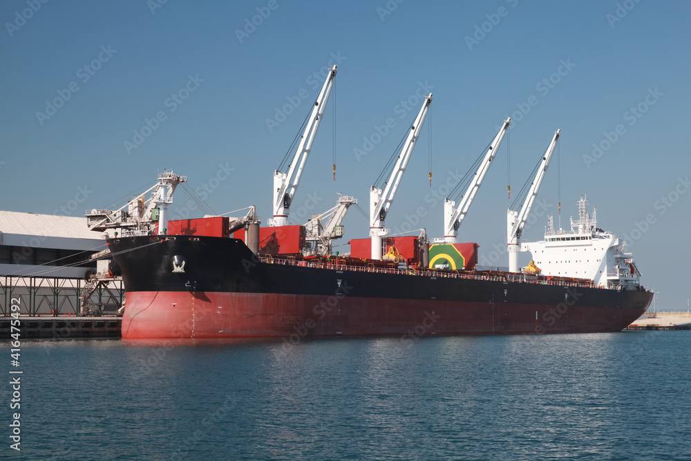 Bulk carrier ship is loading in a port on a sunny day