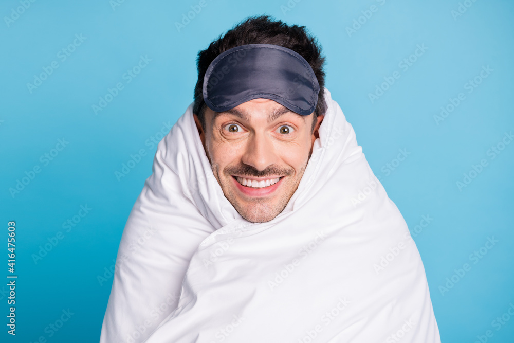Photo portrait of smiling positive man wrapped in duvet isolated on vivid blue colored background Photo portrait of smiling positive man wrapped in duvet isolated on vivid blue colored background