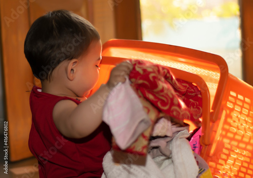 Asian Indian baby girl portrait closeup playing with Cloths bucket. A cute baby girl removing cloth from plastic basket