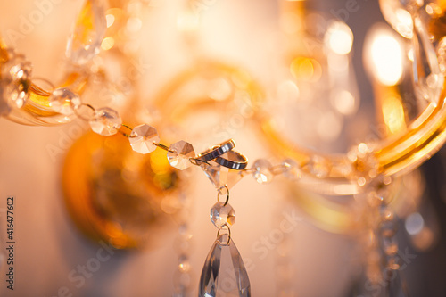 Close up detail view of two wedding rings photographed on a crystal light lamp beautiful warm colors © Dragoș Asaftei