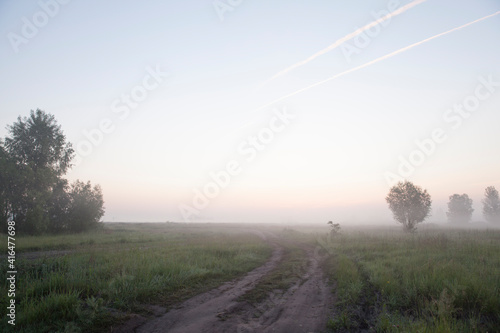 Country road at sunrise. Dawn in a spring meadow.