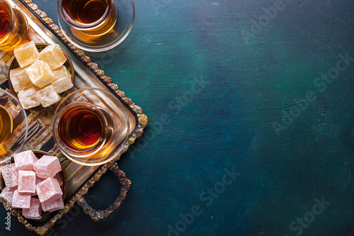 Foto Tea in traditional glass cups  and  turkish delight  on dark blue-green painted wooden background  with empty space for text
