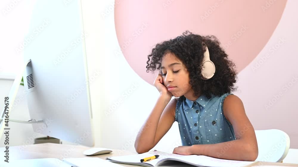 A portrait of bored African girl homeschooling with online teacher. A schoolgirl feels tired of monotonous lessons and lots of homework A portrait of bored African girl homeschooling with online teacher. A schoolgirl feels tired of monotonous lessons and lots of homework