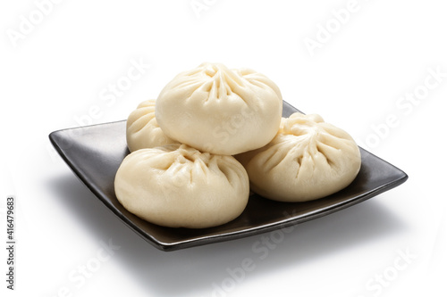 Fresh baozi (Chinese steamed buns) in a black ceramics plate. Isolated on white background.