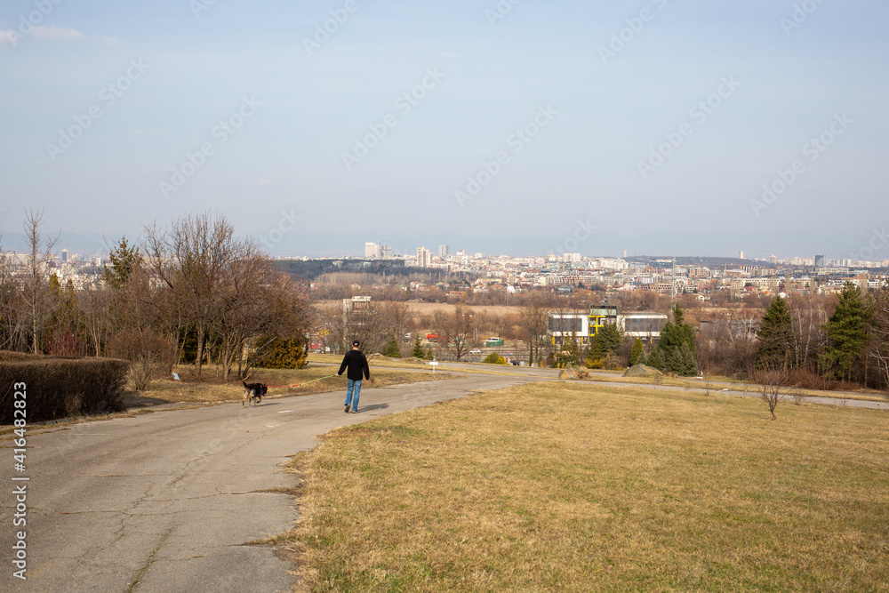 Obraz premium Young man takes his beloved dog for a walk in the park