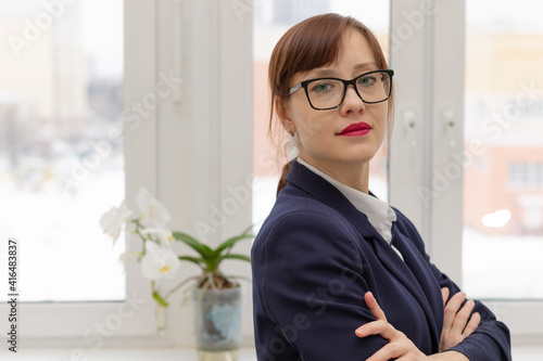 Schilderij op canvas young strict business woman in a blue jacket and glasses is thinking at the wind