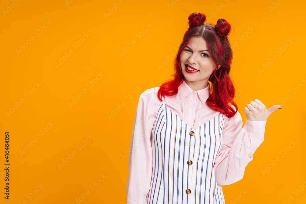Beautiful girl with red hair winking while pointing finger aside Beautiful girl with red hair winking while pointing finger aside