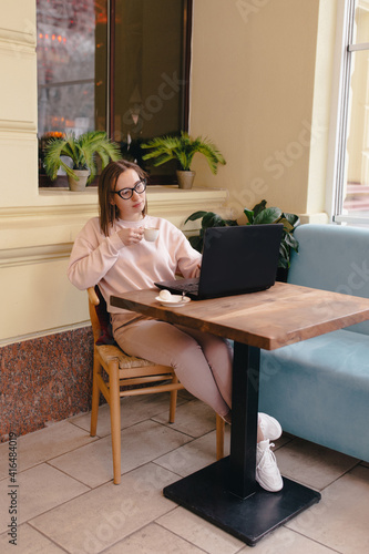 Woman drinking coffee and working at a laptop in a cafe
