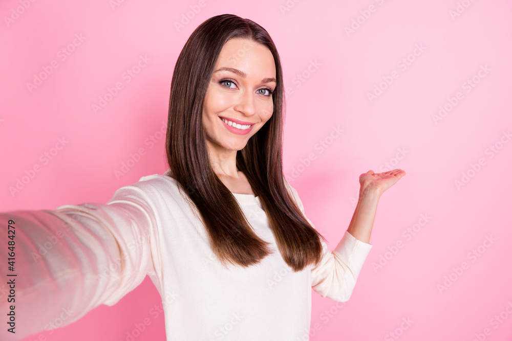 Photo of adorable cheerful girl make selfie arm palm show empty space isolated on pink color background Photo of adorable cheerful girl make selfie arm palm show empty space isolated on pink color background
