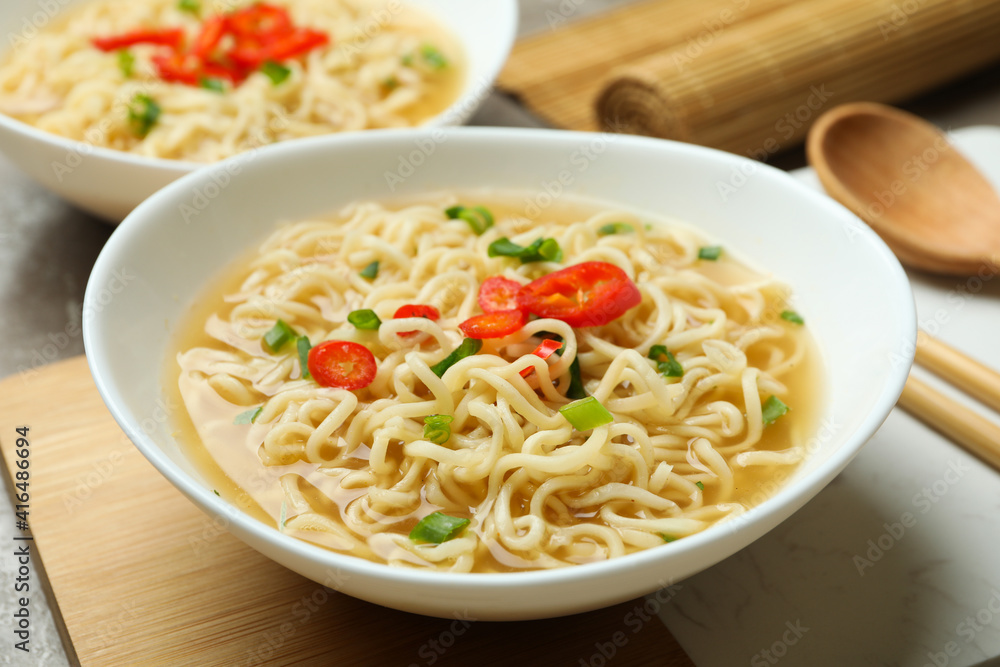 Concept of tasty eating with bowls of noodles on gray background