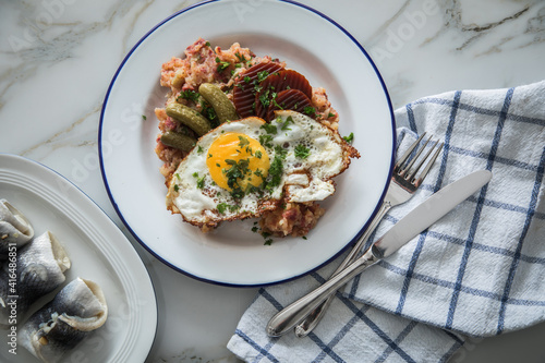 Norddeutscher Hamburger Labskaus mit Rindfleisch Corned Beef, Rote Beete, Kartoffeln, Saure Gurken, Spiegelei und Rollmops auf Emaille Teller photo