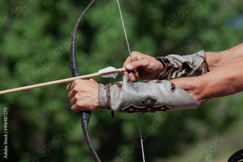 Male hands stretch bowstring close up