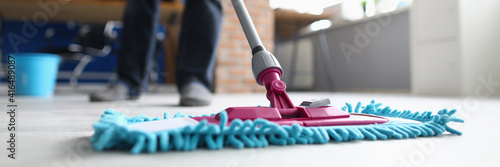 Man with mop washes floor in office. Cleaning company services concept