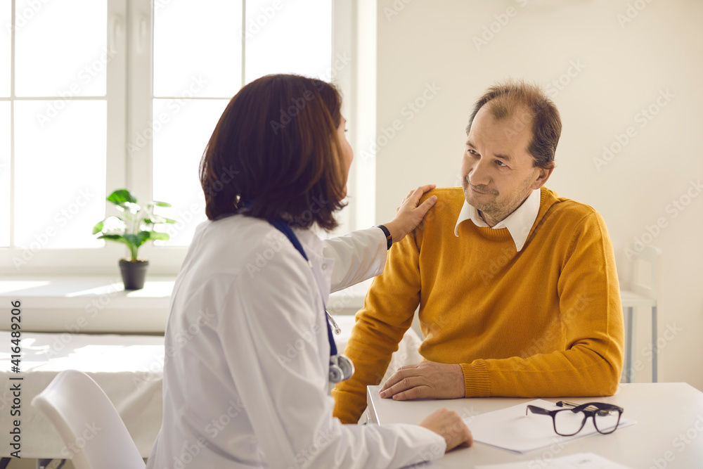 Kind smiling doctor and patient looking at each other. Caring understanding medical worker touches man's shoulder supporting him. Healthcare for senior people, trust, professional consultation concept Kind smiling doctor and patient looking at each other. Caring understanding medical worker touches man's shoulder supporting him. Healthcare for senior people, trust, professional consultation concept