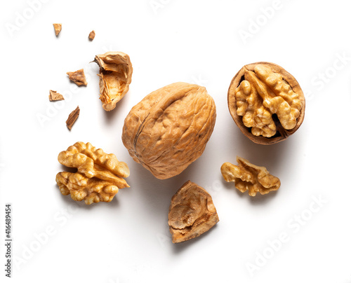 a whole walnut and an open walnut on a white table, top view
 photo