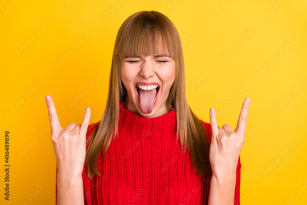 Photo of blond impressed lady show rock sign tongue out wear red sweater isolated on bright yellow color background Photo of blond impressed lady show rock sign tongue out wear red sweater isolated on bright yellow color background