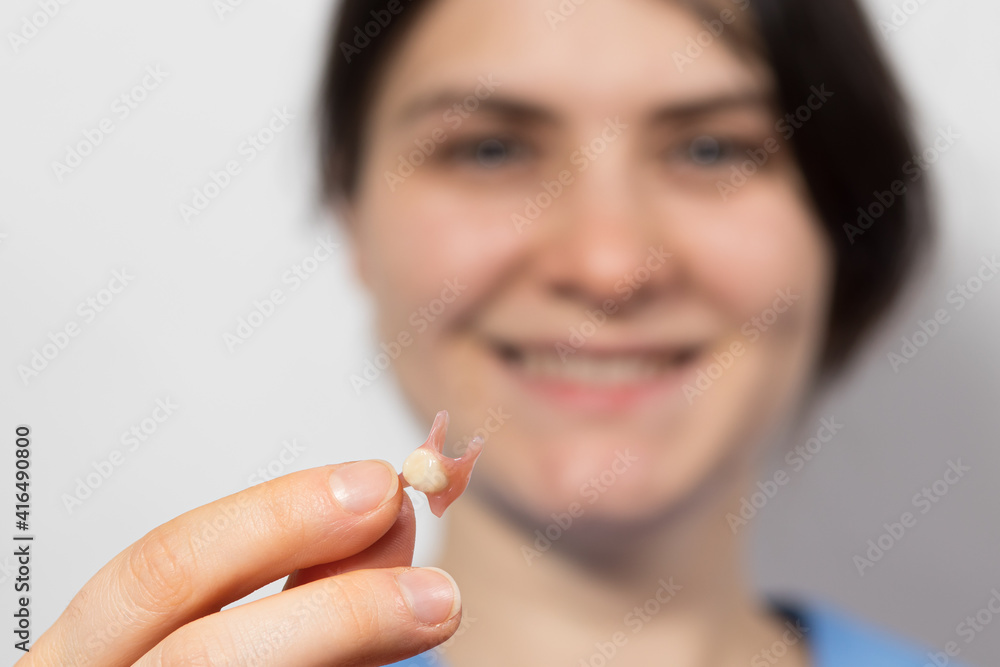 Dentist holding ceramic artificial false unit tooth. Dental prosthesis in gloved hands of the doctor close-up. Dentistry conceptual photo. Prosthetic dentistry. False teeth Dentist holding ceramic artificial false unit tooth. Dental prosthesis in gloved hands of the doctor close-up. Dentistry conceptual photo. Prosthetic dentistry. False teeth