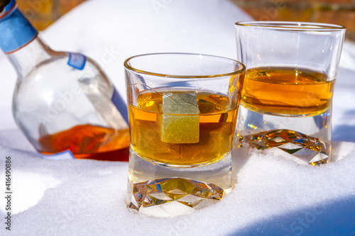 Glasses of cold scotch single malt whisky on white snow