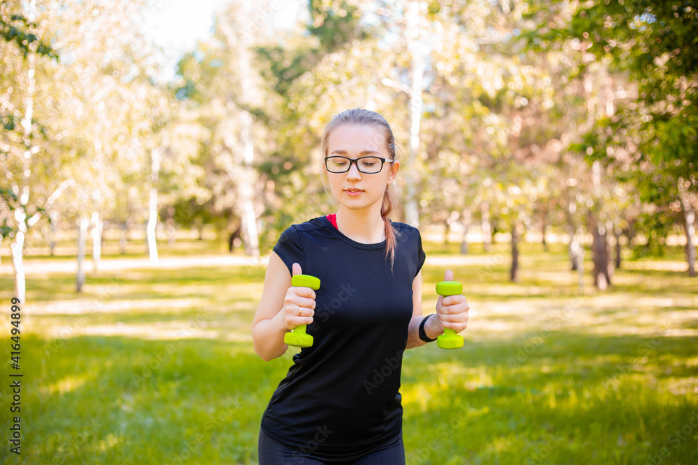 Young woman doing exercise with dumbbells. Healthy lifestyle concept. Sports training in the park. Young woman doing exercise with dumbbells. Healthy lifestyle concept. Sports training in the park.