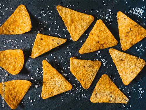 food background. Yellow triangle shaped tortilla chips on black.
