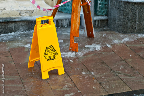 Wallpaper Mural Yellow danger sign. Snow and ice on a slippery sidewalk. Inscription attention in different languages. Plate near the cobblestones in the spring. Torontodigital.ca