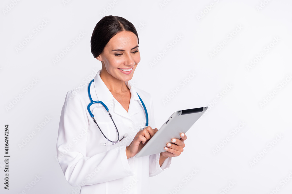 Photo of positive pretty young woman doctor wear formal coat writinh modern gadget empty space isolated white color background Photo of positive pretty young woman doctor wear formal coat writinh modern gadget empty space isolated white color background