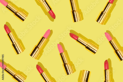 Creative pattern made with red and pink golden lipsticks on bright yellow background. Retro style aesthetic. Trendy and fashion idea. Romantic concept. photo