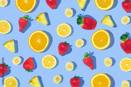 Fototapeta Naklejka Na Ścianę i Meble -  Creative pattern made with strawberries, pineapple, orange, lemon and banana slices on pastel blue background. Creative composition with fruits. Spring or summer idea.