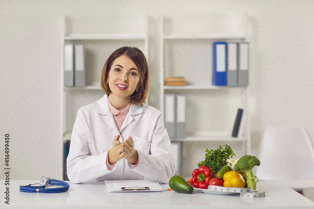 Female nutritionist provides patients with online consultations while sitting in her office. Woman sitting in front of a webcam and talking in a video chat. Concept of proper nutrition.
