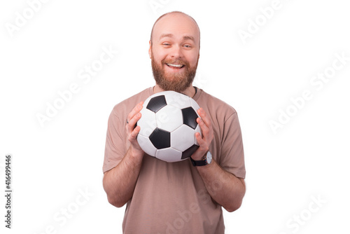 joyful smiling bearded hipster man holding soccer ball and looking at the camera